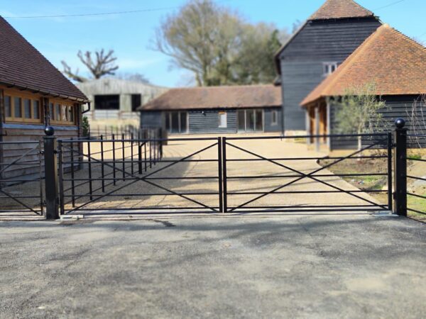 black steel entrance gate with a drive and house in the background